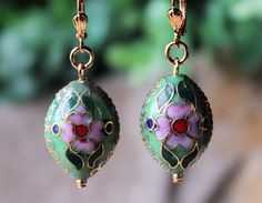 "These beautiful earrings feature a hand painted flower in emerald green on a 3D puff oval. Metal is made of zinc and plated in gold. Hanging from a surgical steel lever-back, it measures 1.5\" in length. Earrings are light weight and sway gracefully as you move about your day. Earrings are painted on both side, round disc measures 1 inch. These delightful dangle earrings are unique, feminine and eye-catching, a great accent to any wardrobe. Available with sculpted clip-on earrings top, please s Green Enamel Wedding Jewelry, Green Enamel Jewelry For Wedding, Traditional Green Flower Earrings, Nickel-free Green Round Flower Earrings, Green Flower-shaped Pierced Earrings, Elegant Hand Painted Green Earrings, Green Flower Drop Earrings, Green Drop Flower Earrings, Green Hand Painted Drop Earrings