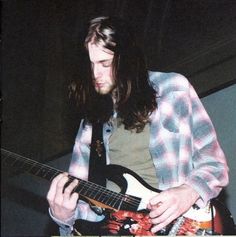 a man with long hair playing an electric guitar