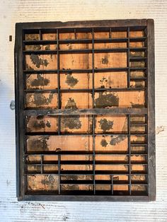 an old metal grate mounted to the side of a white brick wall with peeling paint on it