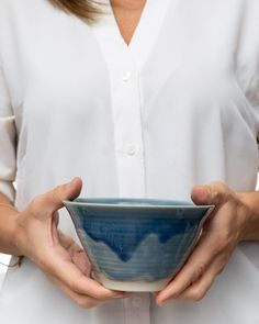 a woman holding a blue and white bowl in her hands while wearing a white shirt