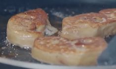 four pieces of meat cooking in a frying pan on top of a gas stove