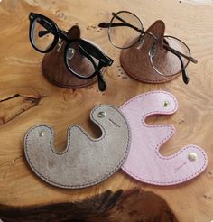 three pairs of eyeglasses sitting on top of a wooden table next to each other