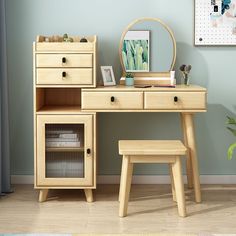 a wooden desk with a mirror, stool and plant on it next to a blue wall