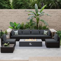 an outdoor living area with couches, tables and a fire pit in the middle