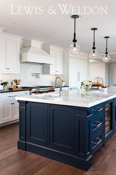 a kitchen with white cabinets and blue island in the center is surrounded by hanging lights