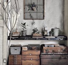 an old dresser with many drawers and plants on it in front of a wall hanging