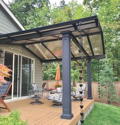 a covered patio with chairs and umbrellas on the deck in front of a house