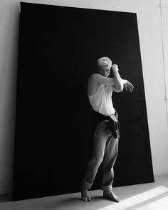 a black and white photo of a man standing in front of a painting