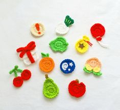 crocheted fruits and vegetables are arranged on a white surface