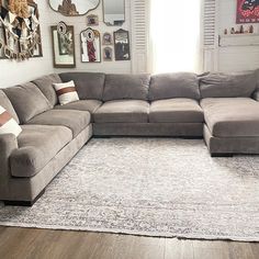 a large sectional couch sitting on top of a wooden floor next to a white rug