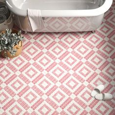 a bath tub sitting next to a toilet and a plant in a vase on the floor