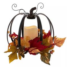 a candle that is sitting inside of a pumpkin shaped holder with leaves and acorns around it