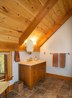 a bathroom with wooden ceiling and tile flooring