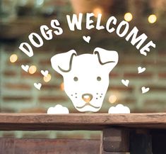 a dog's welcome sticker on the window of a store front with lights in the background