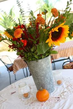 a vase filled with sunflowers on top of a white tablecloth covered table