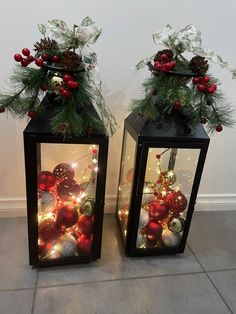 two black lanterns with christmas decorations on them