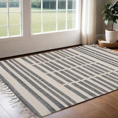 a white and gray striped rug in front of a window with potted plant on the floor