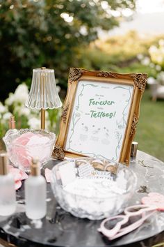 a table topped with a framed sign next to a lamp and other items on top of it