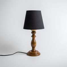 a wooden table lamp with a black shade on the base and a cord attached to it