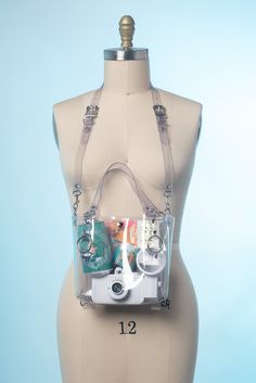 The Clear version of the Mini Harness Tote Bag is the perfect sized every day bag. Made entirely of clear PVC. Snap Closure at the top keeps all the goods inside. Nice sized handles can tuck out of the way into the bag for a more sleek look when wearing with the detachable shoulder strap. The strap is adjustable with two buckles. This is perfect for concerts, festivals, venues, stadiums and events and even workplaces that require a transparent bag and meets most venue and festival size requireme Trendy Pvc Bags For Travel, Trendy Pvc Travel Bag, Clear Plastic Bag With Large Capacity, Trendy Clear Bag With Adjustable Strap, Trendy Clear Shoulder Bag Satchel, Large Capacity Clear Plastic Bag, Daily Use Clear Plastic Bags, Clear Shoulder Bag With Adjustable Strap, Trendy Pvc Bags For Everyday Use