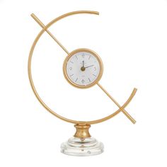 a small clock on top of a glass stand with a gold metal frame and white face