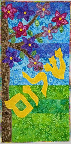 a quilted wall hanging with flowers and trees in the foreground, on a blue background