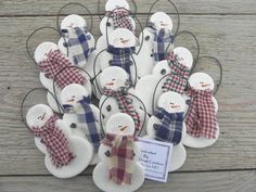 snowmen with plaid scarfs and hats are hanging on the side of a wooden wall