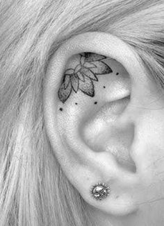 a woman's ear has a flower tattoo on it, and is in the shape of a leaf