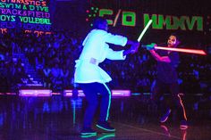 two people in costume are playing with lightsticks on a stage while an audience watches