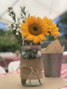 a mason jar with sunflowers and baby's breath is sitting on a table