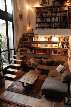 a living room filled with furniture and bookshelves next to a large open window