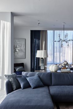 a living room filled with furniture and a chandelier hanging from the ceiling next to a window