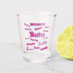 a shot glass with the word boston on it next to a lemon