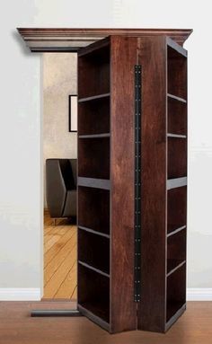 a tall wooden book case sitting on top of a hard wood floor next to a mirror