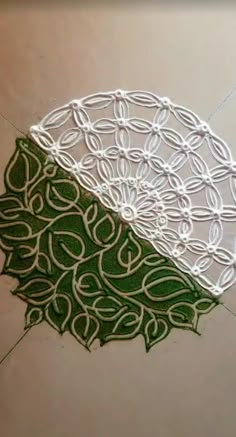 an intricately designed doily on the floor with green and white designs around it