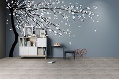 a living room with a tree painted on the wall next to a chair and table