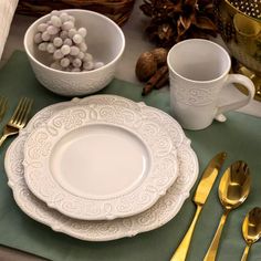 the place setting is ready to be served with gold cutlery and white chinaware