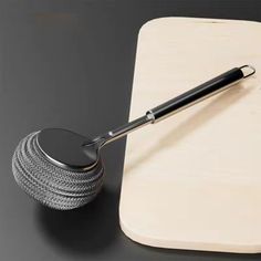 a wooden cutting board with a metal ball on it and a rolling pin next to it