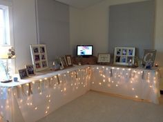 a white counter topped with pictures and lights next to a wall mounted flat screen tv