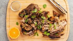 a wooden cutting board topped with meat and garnish