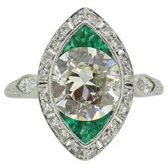 Here we have an outstanding emerald and diamond navette ring, crafted at a time when the Art Deco style was at the height of design. An impressive 2.30ct old cut diamond sits at the centre of the face whilst being top and tailed by a trio of expertly calibre cut emeralds. These focal stones are contained, firstly, within a milgrain setting and are then framed by a single row of 'eight cut' diamonds around the outer edge. A single marquise cut diamond has then been neatly milgrain set at either shoulder. A patterned under-gallery and shank completes the piece and demonstrates expert engraving workmanship and meticulous attention to detail. Condition: Used (Very Good) Weight: 5.0 grams Ring Size: J 1/2 (50) Face Dimensions: 13mm x 11mm Centre Diamond Weight: Approx. 2.30ct Diamond Details: C Navette Ring, Face Dimensions, J 1, Marquise Cut Diamond, Ring Art Deco, Marquise Cut, Art Deco Style, Deco Style, Diamond Gemstone