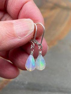 If you are into opals these earrings might be for you. White opal earrings in sterling silver. The minimalist earrings are handmade using white Ethiopian opals and sterling silver materials. A pair of opal stones (6.8 mm wide) with beautiful iridescent fire in mostly green and blue colors are used in the earrings. The earrings are mounted with simple leverback earring wires (shown). The stones are faceted and teardrop-shaped, one of the stones has a few tiny matrix dots. Opal is an October birthstone. The pair measures 1 1/4 inch (3.1 cm) long. These are the earrings you will receive.  Note: Ethiopian opals should be kept away from heat and water as this may alter their fire. The earrings ship in a small organza bag inside a gift box, ready to give... or keep! To see more WireAndPearl ster Dainty Hypoallergenic Opal Earrings, Minimalist Hypoallergenic Opal Earrings, Hypoallergenic Sterling Silver Iridescent Jewelry, Hypoallergenic Opal Drop Earrings, Hypoallergenic Iridescent Sterling Silver Jewelry, Hypoallergenic Opal Dangle Jewelry, Silver Dangle Opal Earrings, Silver Opal Dangle Earrings, Hypoallergenic Opal Earrings For Gift