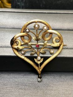 An original Art Nouveau pin done in 18K yellow gold and finished with beautiful enameling, seed pearls and a central small ruby. Dimensions/Weight: Pin measures 1.50" top to bottom with the pearl and 1.1" wide. Pin does protrude past the outer edge of the piece. Condition: There is a solder spot on the left corner as pictured as well as some very minor damage on the back as photographed. Very wearable condition. Elegant Yellow Gold Baroque Brooches, Antique Yellow Gold Brooches With Intricate Design, Yellow Gold Baroque Brooch For Formal Occasions, Formal Yellow Gold Baroque Brooches, Luxury Gold Brooches With Intricate Design, Vintage Yellow Gold Baroque Brooch, Elegant Gold Baroque Brooch, Elegant Gold Baroque Brooches, Antique Yellow Gold Filigree Brooches