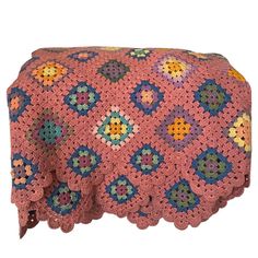 a pink crocheted blanket with multicolored flowers on the top and bottom