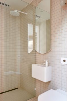 a white sink sitting under a bathroom mirror next to a walk in shower and toilet