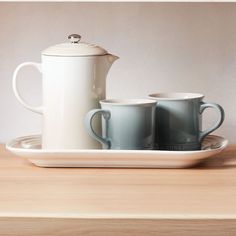 two coffee cups and a tea pot on a tray