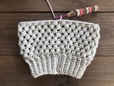 a crocheted dishcloth is hanging from a hook on a wooden surface with yarn