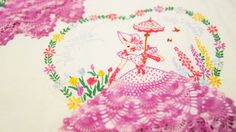 a table cloth with pink crocheted doily on it and an image of a woman holding an umbrella