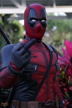 a deadpool figure holding a baseball bat in his right hand and pointing at the camera