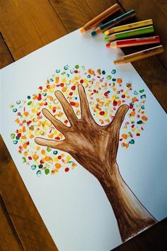 a drawing of a tree with colored pencils next to it on a wooden table